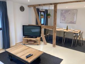 ein Wohnzimmer mit einem Flachbild-TV und einem Tisch in der Unterkunft L’atelier du bricoleur in Marckolsheim