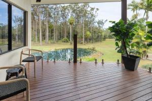 a deck with a view of a pool and trees at The Noosa Ranch- Where Nature meets Luxury in Tinbeerwah