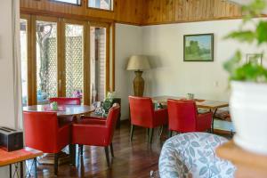 una sala da pranzo con sedie rosse e tavolo di Hotel Posada del Río - Parque Metreñehue a Pucón