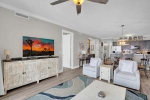 a living room with white furniture and a kitchen at Regency Isle 911 in Orange Beach