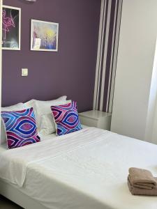 um quarto com uma cama branca e almofadas coloridas em Flamingo Resort em Belgrado