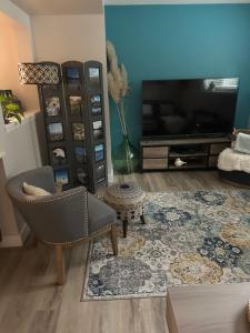 - un salon avec une télévision, une chaise et un tapis dans l'établissement Pleasant Valley Vacation Suite, à Nanaimo