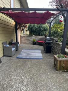 a patio with a red umbrella and a rug at Pleasant Valley Vacation Suite in Nanaimo