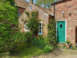 una casa de ladrillo con una puerta verde en Berry Barn en Strubby