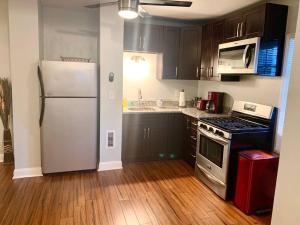 a kitchen with a white refrigerator and wooden floors at The House Hotels - W45th Backhouse - Ohio City District Home - 5 Minutes from Downtown in Cleveland