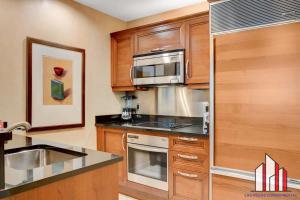 a kitchen with wooden cabinets and a stainless steel appliance at MGM Signature-29-602 1Br 2Ba Balcony Jacuzzi Suite in Las Vegas