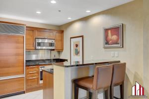 eine Küche mit Holzschränken und eine Bar mit Stühlen in der Unterkunft MGM Signature-20-620 1Br 2Ba Balcony Suite in Las Vegas
