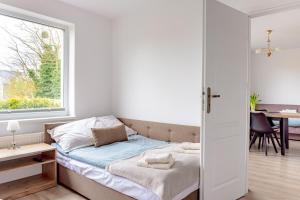 a bed in a room with a window and a table at Pokoje i Apartamenty Marek - Niedaleko Plaży in Ostrowo +32 photos
