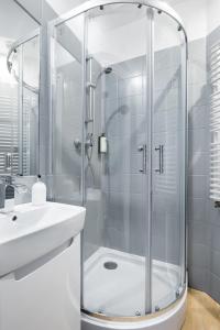 a white bathroom with a shower and a sink at Friendhouse Apartments Starovislna in Krakow