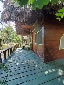 a wooden walkway leading to a cabin with a thatch roof at Hotel Casa Perico in Río Dulce