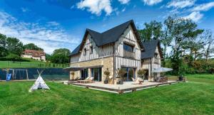 a large house with a large yard with grass at Superbe Villa avec piscine intérieure chauffée in Bonneville-sur-Touques