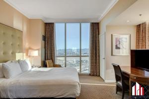 a hotel room with a bed and a desk and a large window at MGM Signature-31-702 1Bedroom 2Bath Balcony Suite in Las Vegas +61 photos