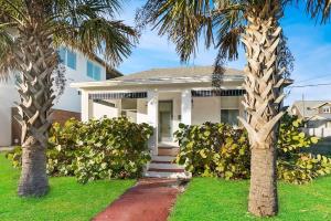 une maison blanche avec des palmiers devant elle dans l'établissement Beach Cottage! 100 Steps to the Sand, Pets OK, Private Deck!, à Saint Augustine