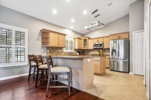 a kitchen with wooden cabinets and a bar with stools at Pool + Hot Tub, Dock, Fishing, Near Beach! in St. Augustine