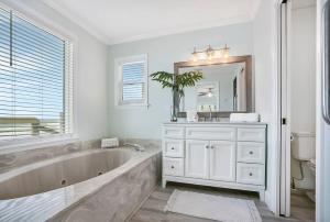 a white bathroom with a large tub and a mirror at Spectacular Oceanfront! Blissful Balconies + BBQ in Saint Augustine +44 photos