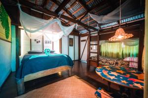 a bedroom with a blue bed and a couch at Hotel Casa Perico in Rio Dulce