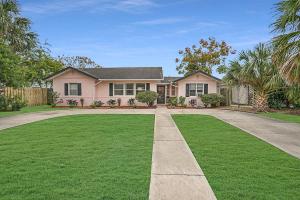 a house with a grass yard and a driveway at Pink House Prime Location Walk to Downtown Dogs OK in Saint Augustine
