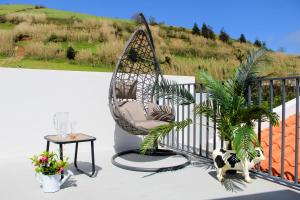 a swing chair sitting on a balcony with a table at Dreamscape Villa in Ponta Delgada