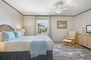 a bedroom with a bed with a ceiling fan and a chair at Canal Home Dock Walk to Beach Kayaks SUP Fishing in Saint Augustine
