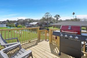 a grill on a deck next to a chair on a porch at Canal Home Dock Walk to Beach Kayaks SUP Fishing in Saint Augustine