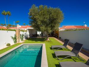 a house with a swimming pool and two lawn chairs at Pasito Blanco Villas in Pasito Blanco