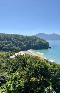 a view of a beach with trees and the ocean at Mirante do Pirata Suítes Bed and Breakfast in Ubatuba