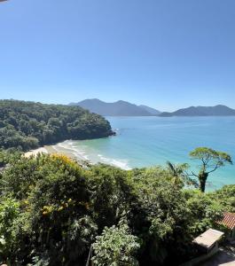a view of a beach with trees and the ocean at Mirante do Pirata Suítes Bed and Breakfast in Ubatuba