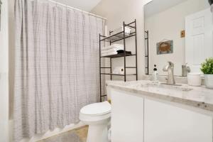 La salle de bains blanche est pourvue de toilettes et d'un lavabo. dans l'établissement 1 Block From St Aug Beach and A Street, Boho Apt with Tropical Vibes, Patio, 3 Parking Spots, à Saint Augustine