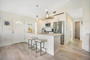 a kitchen with white cabinets and bar stools at Ocean Views Retreat! Renovated Apt with Beach Bikes! in Saint Augustine