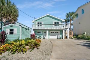 a green house with a balcony and palm trees at Ocean Views Retreat! Renovated Apt with Beach Bikes! in Saint Augustine