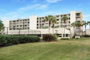 Un gran edificio blanco con palmeras delante. en Upscale Oceanfront Condo with Panoramic Views and Pool, en St. Augustine