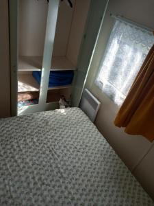 a small bedroom with a bed and a window at Mobil-Home The Duck in Saint-Paul-lès-Dax