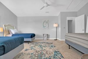 a white bedroom with two beds and a rug at Sapphire Skies! Sweet Beach Condo Steps from the Sand and Surf in St. Augustine