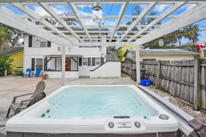 a hot tub in a backyard with a pergola at Uptown Treasure with Spa Dogs Ok Dreamy Patio in St. Augustine