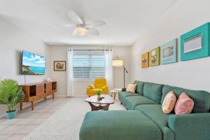 a living room with a green couch and a yellow chair at The Atomic Burst 50s Mid Century Apt in the Heart of St Aug Beach Steps to Sand Bites and Drinks in Saint Augustine