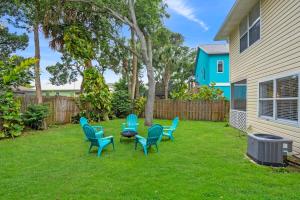 a yard with chairs and a table and a fence at The Atomic Burst 50s Mid Century Apt in the Heart of St Aug Beach Steps to Sand Bites and Drinks in Saint Augustine