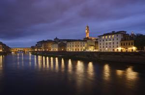a river with buildings and a bridge at night at Hotel Balestri - WTB Hotels in Florence