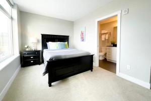 a white bedroom with a bed and a bathroom at 2BR 2BA Top Floor DT GR Penthouse Parking &Gym in Grand Rapids