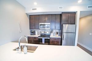 uma cozinha com armários de madeira e um frigorífico de aço inoxidável em Luxury King Bed Apt in Downtown GR em Grand Rapids