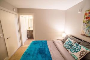 een slaapkamer met een bed met een blauwe deken erop bij Luxury King Bed Apt in Downtown GR in Grand Rapids