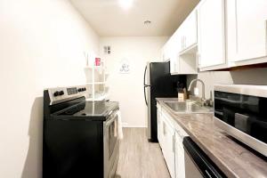 a kitchen with a black refrigerator and a sink at 2BR and 2BA Beer City Flat with Pool Gym and Parking in Grand Rapids