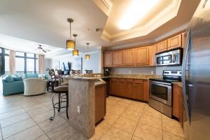 a kitchen with wooden cabinets and a living room at Phoenix West II 2307 Lazy River + Waterslide in Orange Beach