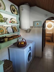 uma cozinha com uma máquina de lavar roupa e uma cesta de frutas em Casa da Fonte em Alviobeira