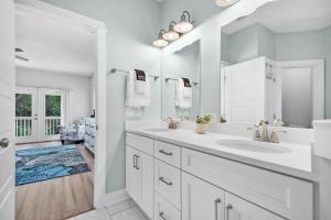 a white bathroom with a sink and a mirror at Treetop Terrace 250 Steps to Beach Heated Swim Spa in Saint Augustine +51 photos