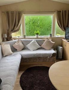 um sofá com almofadas em frente a uma janela em 2-Bed Caravan in Mablethorpe sea front location em Mablethorpe