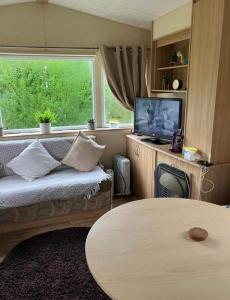 uma sala de estar com um sofá, uma mesa e uma janela em 2-Bed Caravan in Mablethorpe sea front location em Mablethorpe