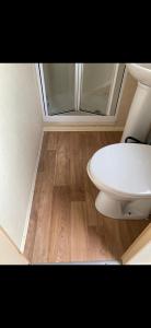 uma casa de banho com WC e piso em madeira em 2-Bed Caravan in Mablethorpe sea front location em Mablethorpe