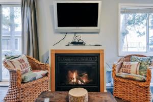 un soggiorno con camino e TV sopra di Beach Club of Oscoda Garden Cottage on the Lake a Oscoda