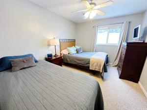 1 dormitorio con 2 camas y ventilador de techo en Beach Club of Oscoda - The Lakeshore Cottage en Oscoda