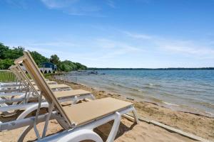 a row of lawn chairs sitting on a beach at Fife Lake Lodge Multi-Level Lake View King Suite in Fife Lake +45 photos